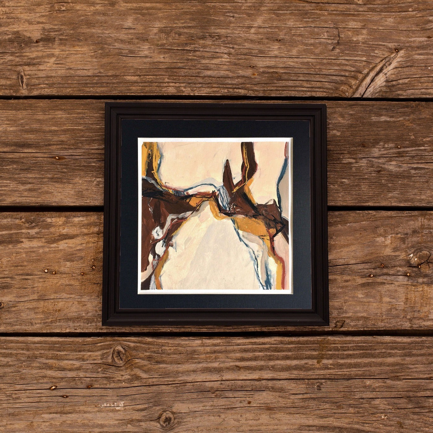 One-of-a-kind mixed media artwork in warm gray, white, light ochre, raw sienna, burnt sienna, and black colors. Intuitive composition in the artist's art practice. Framed in black, matt paper frame. Mockup: Designed by denamorado / Freepik